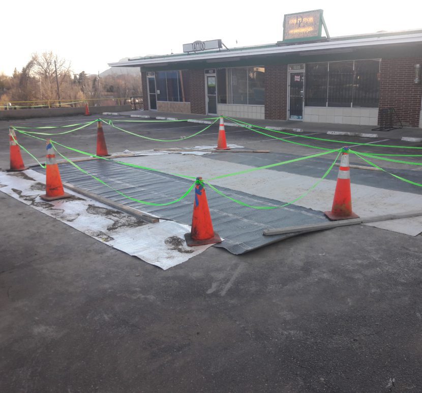 Construction site with safety cones around a covered area on the ground.