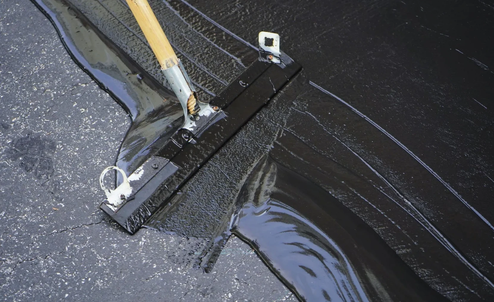 Applying sealant on asphalt driveway