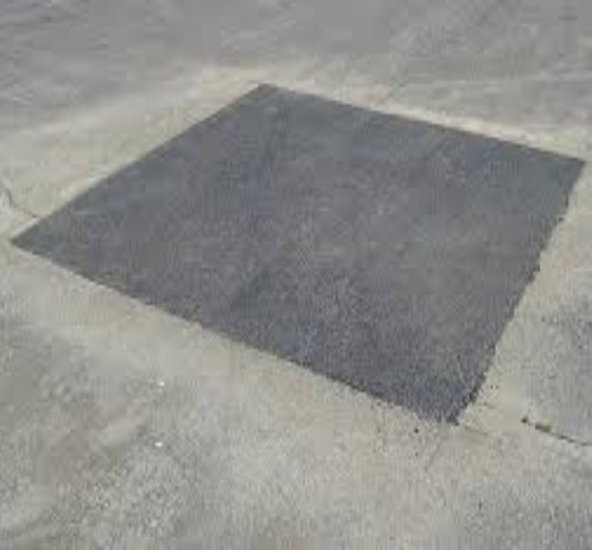 A freshly patched square on a concrete surface.
