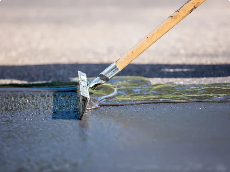 Worker smoothing asphalt surface with a rake